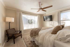 Carpeted bedroom featuring ceiling fan and ornamental molding