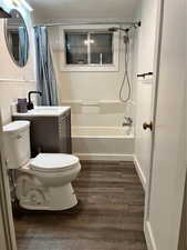 Full bathroom featuring hardwood / wood-style floors, vanity, toilet, and shower / bathtub combination with curtain