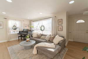 Living room with light wood-type flooring and ornamental molding