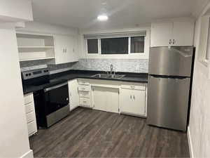 Kitchen with sink, tasteful backsplash, dark hardwood / wood-style flooring, white cabinetry, and stainless steel appliances