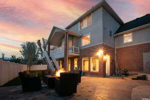 Back house at dusk with a covered deck and covered patio and an outdoor gas fire pit