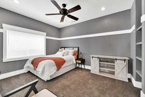 Bedroom featuring ceiling fan and dark carpet