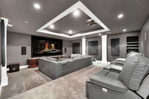 Carpeted home theater with a tray ceiling and decorative columns