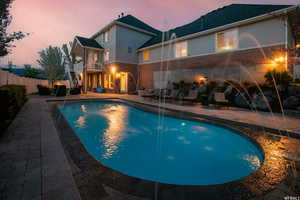 Pool at dusk with pool water feature and a sundeck