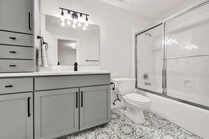 Full bathroom featuring tile patterned flooring, vanity, toilet, and combined bath / shower with glass door