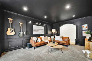 Living room featuring ornate columns, crown molding, and carpet floors