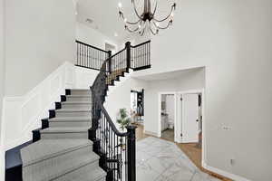 Stairway featuring a towering ceiling and an inviting chandelier