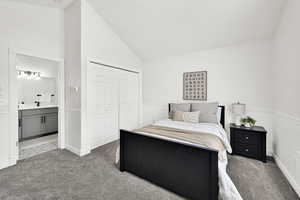 Carpeted bedroom featuring vaulted ceiling, connected bathroom, and a closet