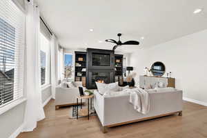 Family room with a large fireplace, a healthy amount of sunlight, and light hardwood / wood-style floors