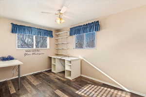 Home office with ceiling fan and dark wood-type flooring