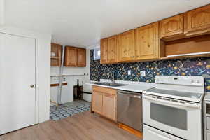 Kitchen with sink, stainless steel dishwasher, decorative backsplash, white range with electric stovetop, and light hardwood / wood-style floors