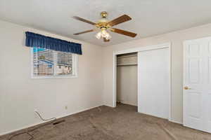 Unfurnished bedroom with ceiling fan, a closet, carpet, and a textured ceiling