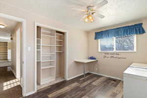 Interior space featuring a textured ceiling, ceiling fan, and dark wood-type flooring