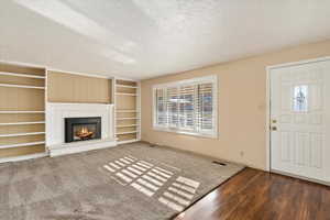 Unfurnished living room featuring dark hardwood / wood-style flooring and a textured ceiling