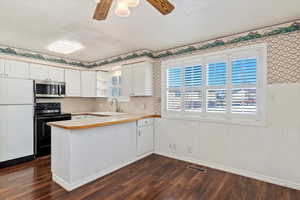 Kitchen featuring kitchen peninsula, dark hardwood / wood-style flooring, black electric range oven, white refrigerator, and white cabinetry