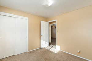 Unfurnished bedroom featuring a closet, carpet, and a textured ceiling