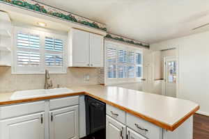 Kitchen with white cabinetry, dishwasher, sink, a healthy amount of sunlight, and kitchen peninsula