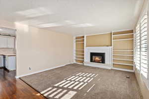 Unfurnished living room featuring a textured ceiling and dark wood-type flooring