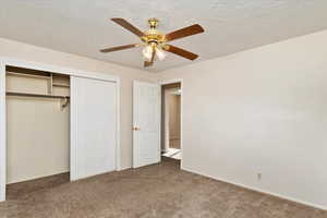 Unfurnished bedroom with carpet flooring, ceiling fan, a textured ceiling, and a closet