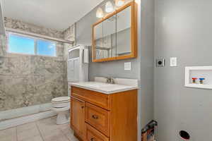 Bathroom with tile patterned flooring, vanity, toilet, and an enclosed shower