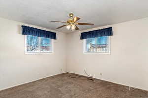 Carpeted spare room featuring a textured ceiling and ceiling fan