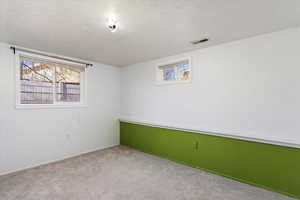 Basement with light carpet and a textured ceiling