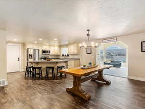 Dining area with a chandelier, a textured ceiling, and dark wood-type flooring