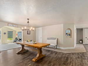 Dining space featuring hardwood / wood-style floors, a textured ceiling, and an inviting chandelier