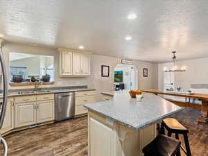 Kitchen featuring sink, stainless steel dishwasher, cream cabinets, a breakfast bar area, and a kitchen island