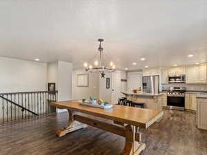 Dining room with dark hardwood / wood-style floors, a textured ceiling, and an inviting chandelier