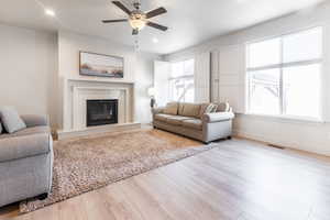 Living room featuring light wood-type flooring, a wealth of natural light, and ceiling fan