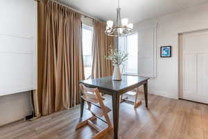 Dining room with light hardwood / wood-style floors, a wealth of natural light, and a notable chandelier