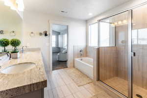 Primary bathroom featuring tile patterned floors, vanity, a textured ceiling, and independent shower and bath