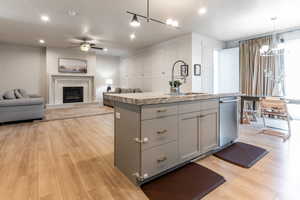 Kitchen featuring sink, stainless steel dishwasher, a center island with sink, and light hardwood / wood-style floors