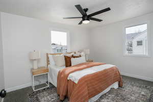 Bedroom with multiple windows, a textured ceiling, dark carpet, and ceiling fan