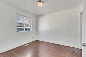 Empty room with dark wood-type flooring