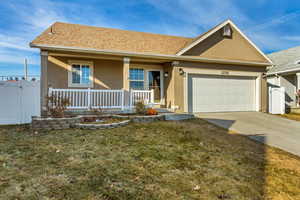 View of front of property with covered porch, a front yard, and a garage