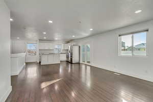 Unfurnished living room with sink and dark wood-type flooring