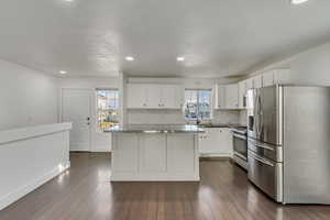 Kitchen with white cabinetry, sink, a center island, stainless steel appliances, and backsplash