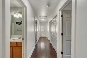 Hallway with a textured ceiling, dark wood-type flooring, and sink