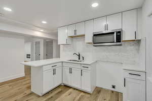 Kitchen with light hardwood / wood-style floors, white cabinetry, and sink