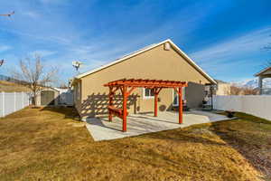 Back of house featuring a pergola, a lawn, a patio, and a storage shed