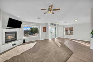 Unfurnished living room featuring wood-type flooring and ceiling fan