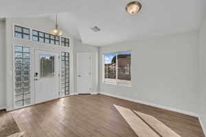 Foyer entrance with light hardwood / wood-style flooring and vaulted ceiling