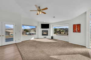 Unfurnished living room featuring ceiling fan, plenty of natural light, lofted ceiling, and french doors