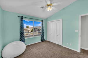 Living area featuring carpet floors, vaulted ceiling, and ceiling fan