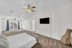 Carpeted bedroom featuring ceiling fan and vaulted ceiling