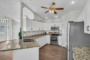 Kitchen with kitchen peninsula, appliances with stainless steel finishes, white cabinetry, and sink