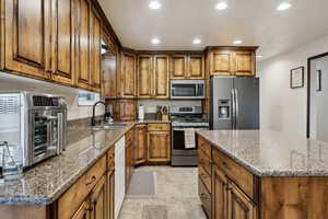 Kitchen with stone counters, a kitchen island, sink, and appliances with stainless steel finishes