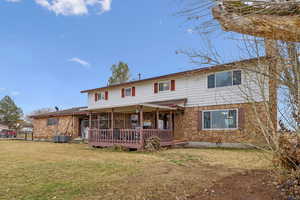 View of front facade featuring a deck, central air condition unit, and a front lawn